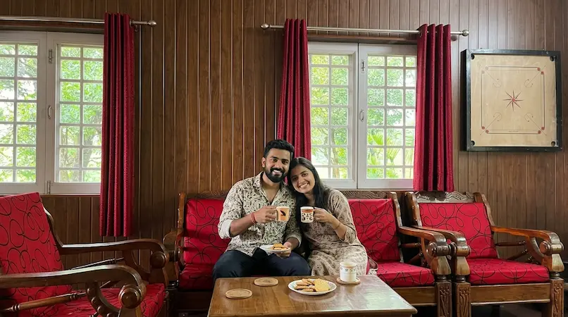 Couple relaxing on sofa with tea in spacious 1BHK living room at Bimal Farm