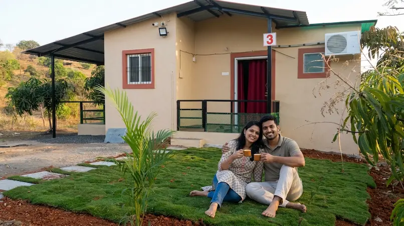 Couple enjoying morning tea on private green lawn outside Cottage 3 with mountain views at Bimal Farm
