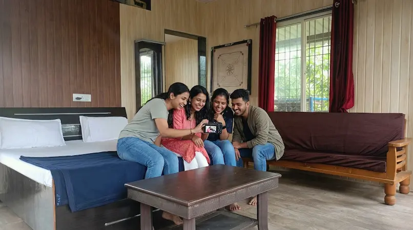 Friends laughing and reviewing trip photos together inside Cottage Type C studio room at Bimal Farm